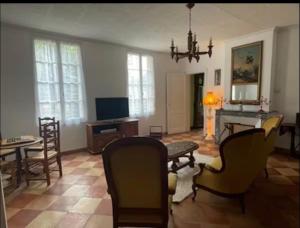 a living room with a table and chairs and a television at Le logis d Adrien in Saint-Magne-de-Castillon