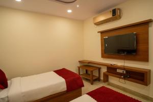 a bedroom with a bed and a flat screen tv at Magnet Hotel in Vijayawāda