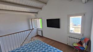 a room with a tv and a chair and a window at Lagunahome Beatrice in Chioggia