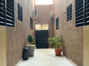 a hallway with potted plants and a black door at La MAISON SEONE SILVER in Abidjan