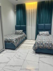 two beds in a room with green curtains at Tarek in Oran