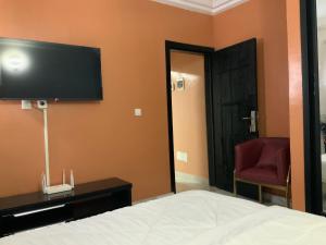 a bedroom with a bed and a tv on the wall at La MAISON SEONE SILVER in Abidjan