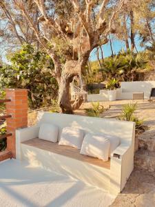 a white bench with pillows on it in front of a tree at Villa Wanderlust Sitges Hills Exclusive pool only families in Olivella +27 photos