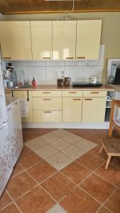 a kitchen with white cabinets and a tile floor at Zinnia Vendégház in Nagyrada