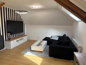 a living room with a black couch and a flat screen tv at Casa del Mondo 3 in Sankt Aldegund