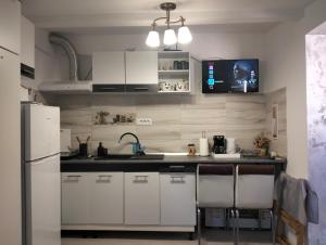 a kitchen with white cabinets and a tv on the wall at Garsoniera 20m2 anexată la casa proprietarului in Botoşani