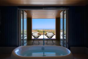 a bath tub in a room with a balcony with two chairs at THE SECOND Chousei Beach Village in Jōnouchi