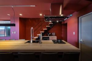 a kitchen with red walls and a wooden table with chairs at THE SECOND Chousei Beach Village in Jōnouchi