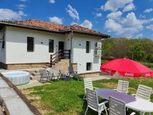 a house with a table and chairs and a red umbrella at Bachvarov house Бъчваровата къща in Palitsi