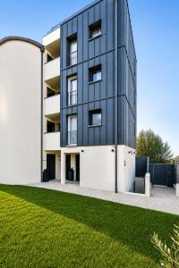 a black building with a lawn in front of it at JIJI Suites Sénart in Combs-la-Ville
