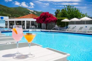 two wine glasses sitting on a table next to a swimming pool at Meandros Boutique & Spa Hotel - Adults Only in Kalamaki