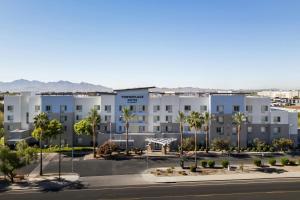 a large white building with palm trees in a parking lot at TownePlace Suites by Marriott Phoenix Goodyear in Goodyear