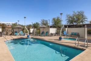 a swimming pool at a resort with chairs and tables at TownePlace Suites by Marriott Phoenix Goodyear in Goodyear