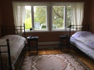 two beds in a bedroom with a window at Hen stasjon Venteværelset in Hen
