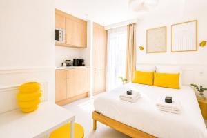 a bedroom with a white bed with yellow accents at JIJI Suites Sénart in Combs-la-Ville