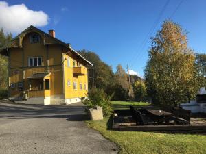 a yellow house with a picnic table in front of it at Hen stasjon Venteværelset in Hen