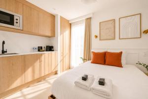 a bedroom with a large white bed with two towels at JIJI Suites Sénart in Combs-la-Ville