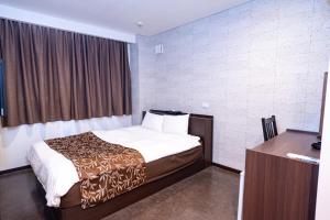 a hotel room with a bed and a desk at ホテル ニューウェーブ in Okayama