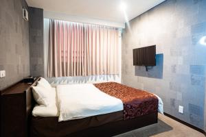 a small bedroom with a bed and a television at ホテル ニューウェーブ in Okayama