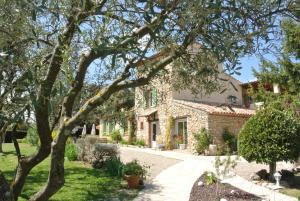 una casa de piedra con un árbol en el primer plano en La Vieille Bastide, en Flayosc