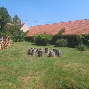 a pile of logs in a yard with a house at Statek VRANČ - U Kačenky in Bítov