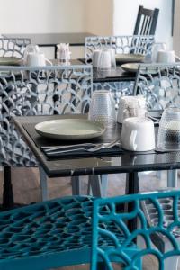 a table with plates and utensils on top at Hôtel Saint-Florent, à 2 pas du Théatre Antique d'Orange in Orange