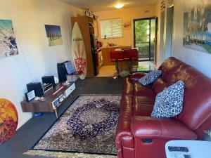 a living room with a leather couch and a surfboard at Scarborough Beach Shack in Perth