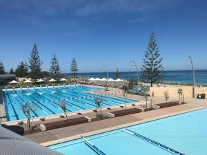 a large swimming pool with the ocean in the background at Scarborough Beach Shack in Perth