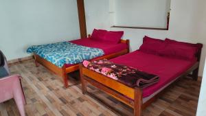 two beds with red sheets in a room at Emerald home stay in Kodaikānāl