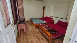 a small room with two beds and a chair at Emerald home stay in Kodaikānāl