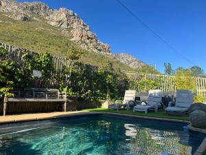 a swimming pool with two lawn chairs and two lawn chairs at 78on5th in Hermanus in Hermanus +8 photos