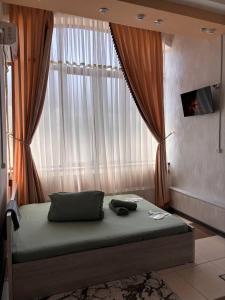 a bed in a room with a large window at Отель "VOSTOK" in Yalanghoch