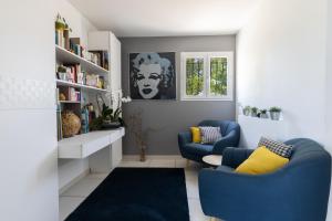 a living room with two blue chairs and bookshelves at Olympe de Provence in Caromb