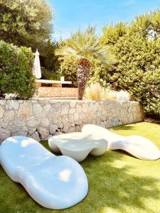 two white chairs sitting on the grass in a garden at Villa Wanderlust Sitges Hills Exclusive pool only families in Olivella