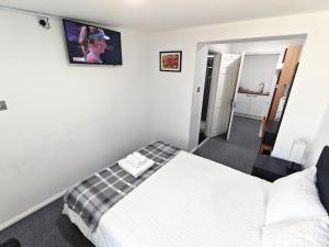 a bedroom with a bed and a tv on the wall at Hawthorn Studio - Self Contained One-Bed Studio Flat in Oxford
