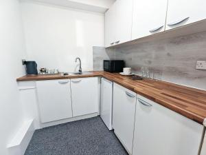 a kitchen with white cabinets and a wooden counter top at Hawthorn Studio - Self Contained One-Bed Studio Flat in Oxford +14 photos