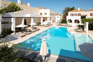 a pool with chairs and umbrellas next to a building at Nissia Traditional Residences Spetses in Spetses