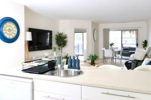 a kitchen with a sink and a living room at The Olive Edit in Batemans Bay