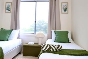 a bedroom with two beds and a window at The Olive Edit in Batemans Bay