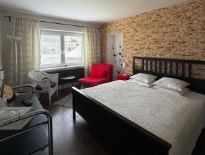 a bedroom with a large bed and a red chair at Apartments Centrum in Rožnov pod Radhoštěm