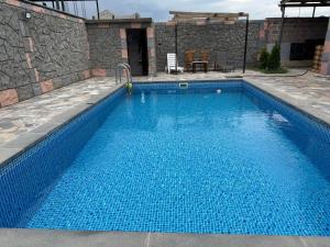a swimming pool with blue water in front of a stone wall at Дом с бассейном в Ереване in Davitashen