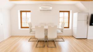 a white dining room with a table and white chairs at Valora Central Apartment in Vrhnika