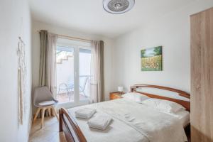 a white bedroom with a bed and a balcony at Iraklitsa View in Iraklitsa