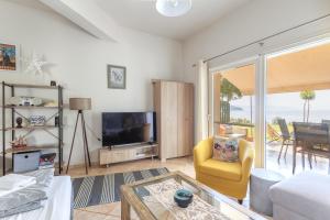 a living room with a tv and a yellow chair at Iraklitsa View in Iraklitsa