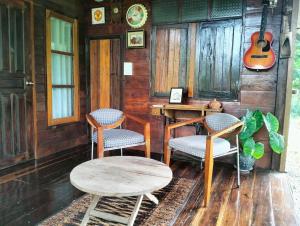 a room with a table and chairs and a guitar at Tamarind nest in Sai Yok
