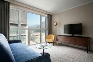 a living room with a blue couch and a large window at Four Points Sheraton Bolzano Bozen in Bolzano