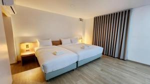 a bedroom with a large bed with white sheets at Mark Four Place Hotel in Phrae