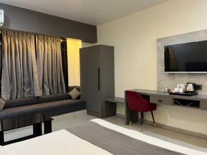 a hotel room with a bed and a desk and a television at Ace Inn Hotel in Nagpur