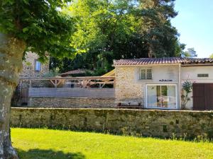 a house with a stone wall and a fence at Relaxing Gite aux fil de l'eau in Sainte-Colombe-sur-lʼHers