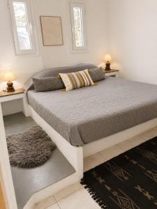 a large bed in a bedroom with two windows at The simple two-bedroom house at Klima Beach in Samos